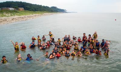 a large group of children at camp swimming in the ocean